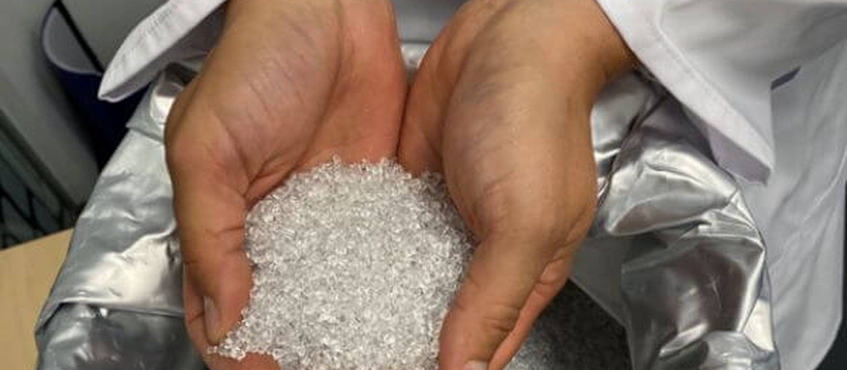 Mãos segurando pellets de material para impressão 3D