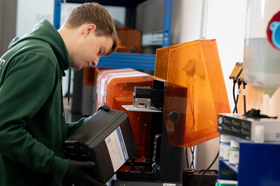 Profissional operando uma impressora 3D industrial na bancada