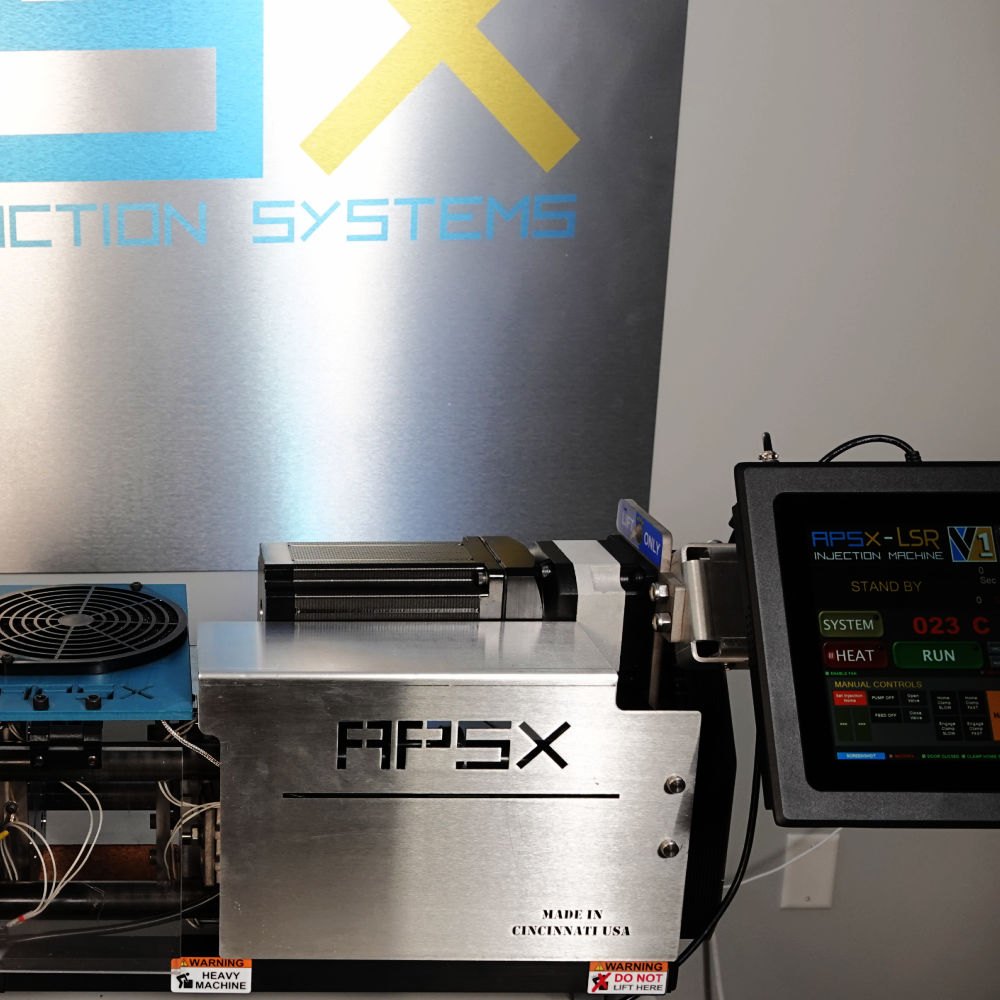 Injetora APSX-LSR sobre a bancada, com a carenagem de aço inox e a tela de comando