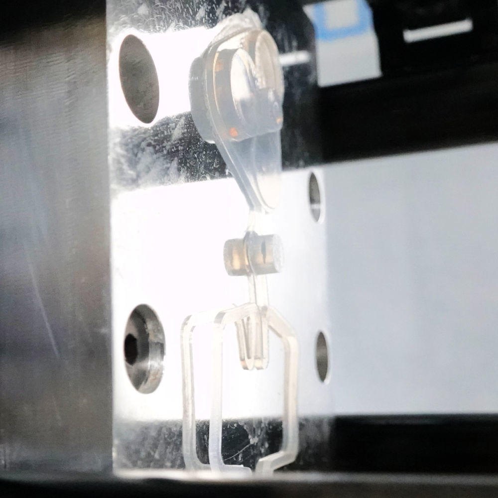 Peça de silicone transparente presa no molde de alumínio da APSX-LSR depois da injeção